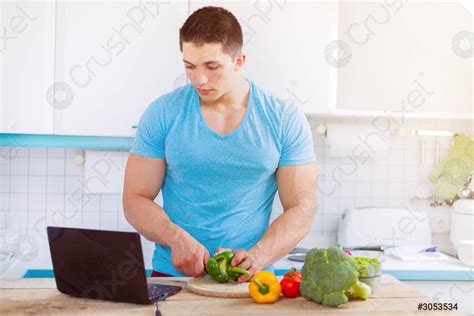 Young man cooking healthy meal vegetables computer internet eating ...