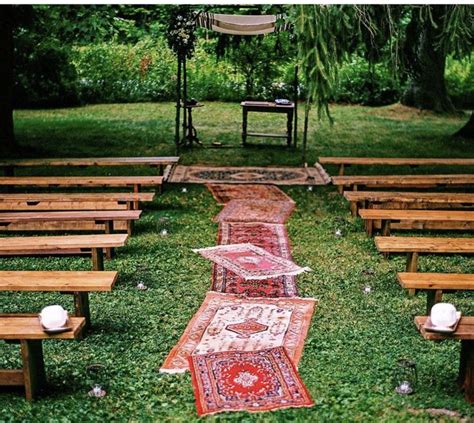an outdoor area with benches and rugs on the grass
