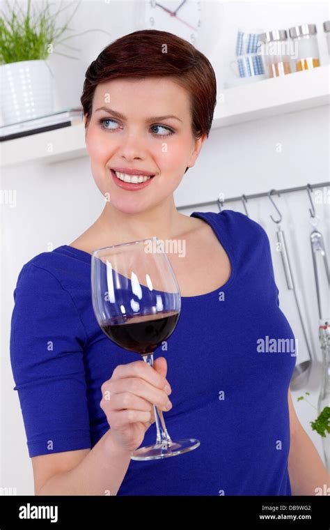 young woman enjoying a glass of red wine in her modern kitchen Stock ...