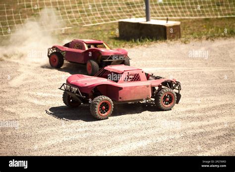 Two small radio controlled model cars racing in the dust. Miniature ...