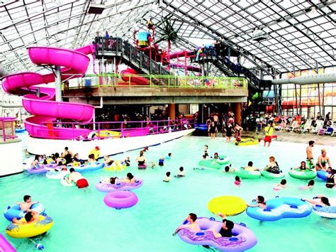 many people are in the water at an indoor swimming pool with large rafts and colorful slides