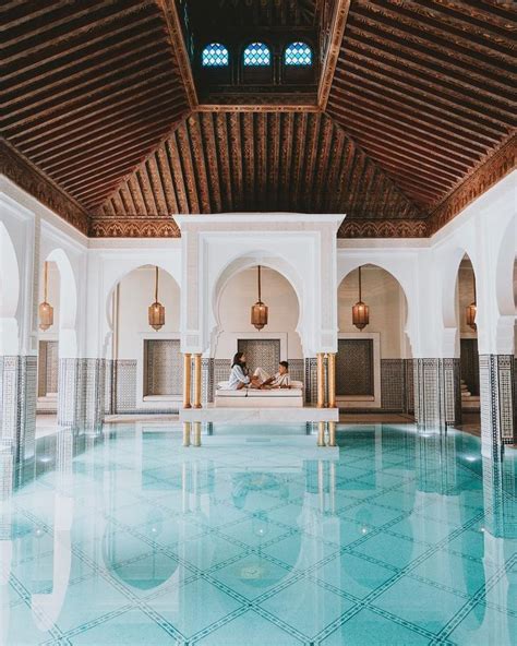 an indoor swimming pool with tiled floors and wooden ceilinging, surrounded by white walls