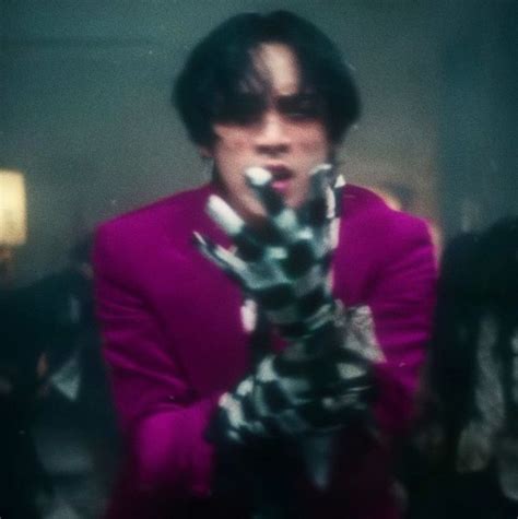 a man in a pink jacket holding up his hand with an animal print glove on it