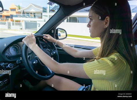 Teenager girl concentrating while driving car through city street Stock ...