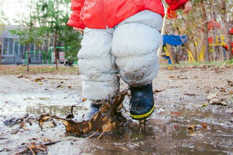 little kid jumping in a puddle in the park 35062610 Stock Photo at Vecteezy