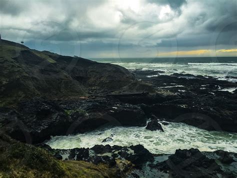 black coastline with body of water splashing through rock groynes ...