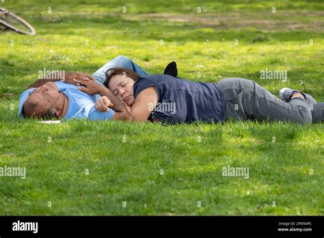 A couple, presumably husband & wife, take an afternoon nap in Flushing Meadows Corona Park in ...