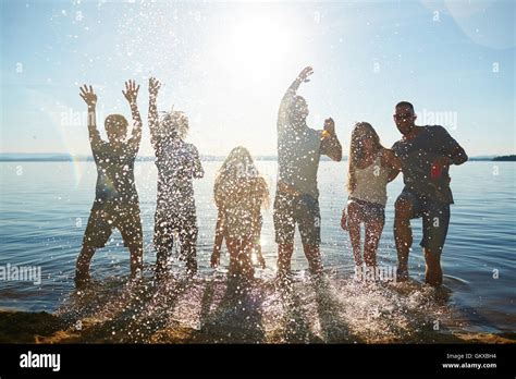 Young people standing in the water and splashing water Stock Photo - Alamy