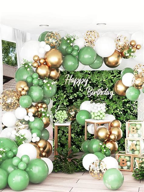 a green and gold birthday party with balloon garlands, balloons, and greenery