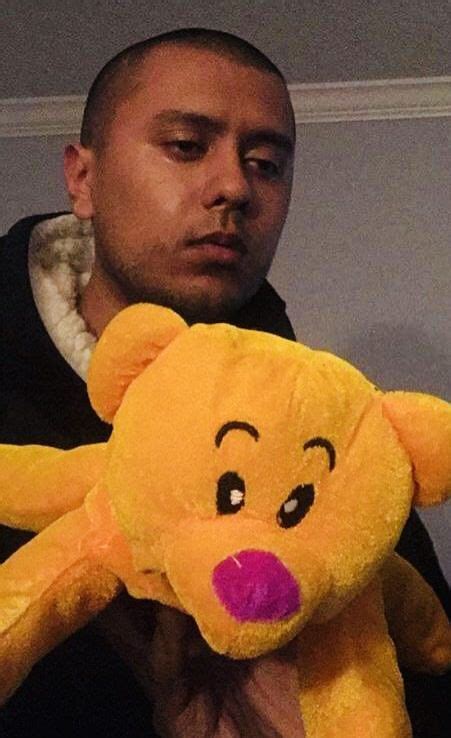 a man is holding a large yellow teddy bear with pink nose and eyes on his chest