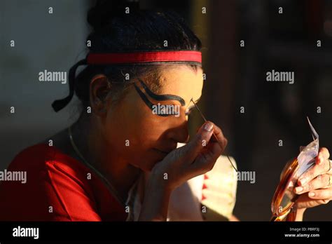 A Koodiyattam artist getting ready for performance by putting face paint. Artist puting face ...