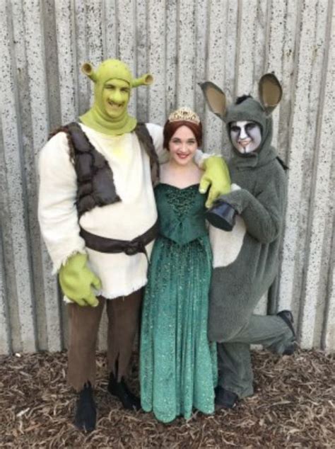 two people in costume standing next to each other near a wall with a metal fence behind them