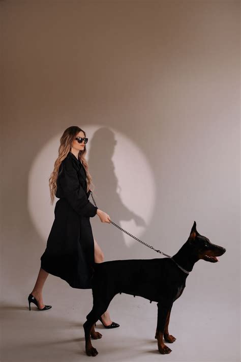 a woman is walking her dog on a leash with the shadow of a man behind her