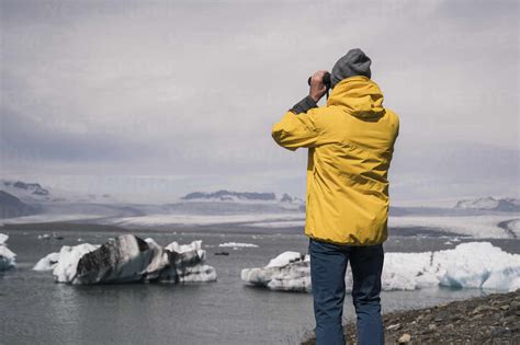 Mature man watching Vatnajokull glacier with binoculars, Iceland stock photo