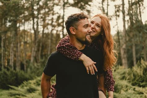 Premium Photo | Strong handsome smiling man is holding piggyback his wonderful woman in a park