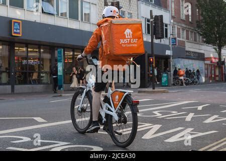 Just Eat courier delivery rider in orange uniform and Just Eat Scooter ...