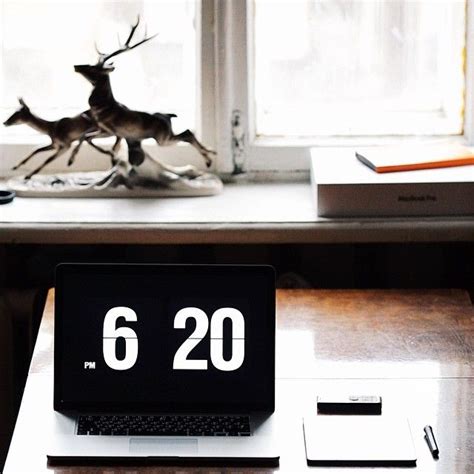 a laptop computer sitting on top of a wooden desk next to a statue of a deer