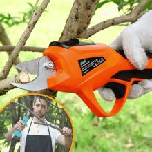 an orange and black pair of scissors being used to prune tree branches in a yard