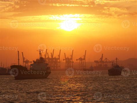 Cargo ship and cranes at port harbour in Tanjung Perak Surabaya with sunset sky background ...