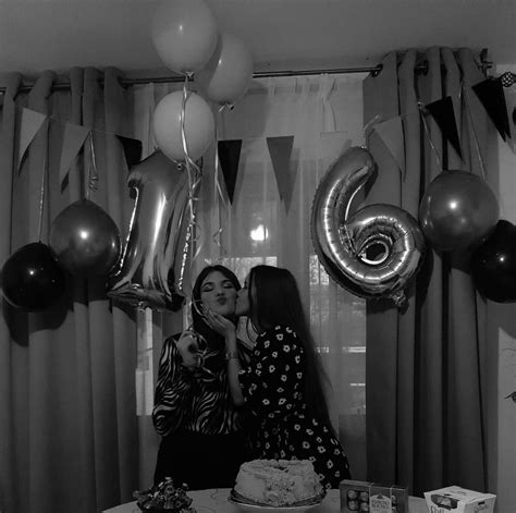 two women standing in front of a table with cake and balloons