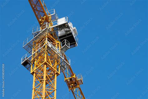 Yellow tower crane with cabin bottom view, blue clear sky background copy space. New tower crane ...