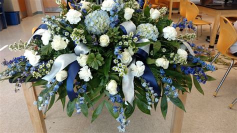 Blue, white, silver casket spray (funeral flowers) with hydrangeas, roses, delphinium. Cowboys ...