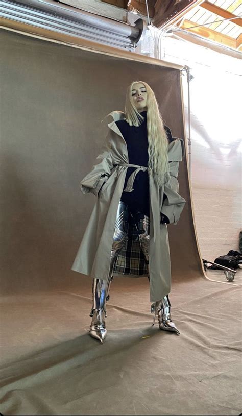 a woman is standing in front of a backdrop wearing silver boots and a ...