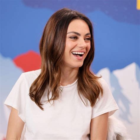 a smiling woman sitting in front of a blue and red wall with snow written on it