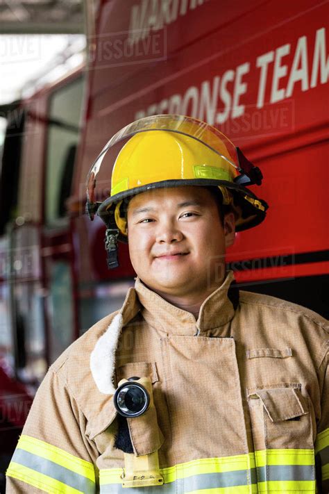 Smiling Chinese fireman standing near fire truck - Stock Photo - Dissolve