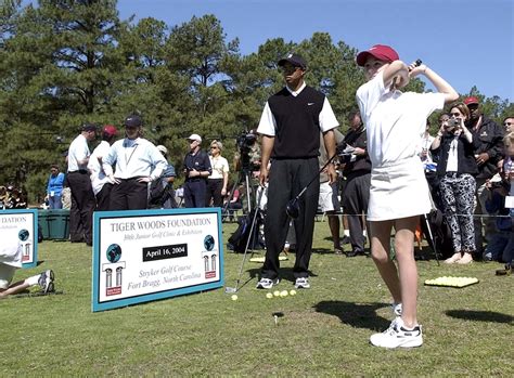 Golfer Tiger Woods watches the swing of 11-year-old Emily Gaylord ...