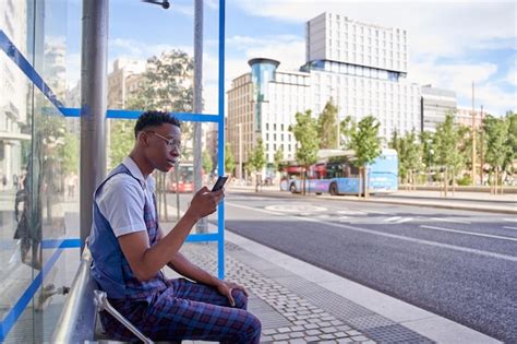 Premium Photo | Man waiting at bus stop while looking at smart phone