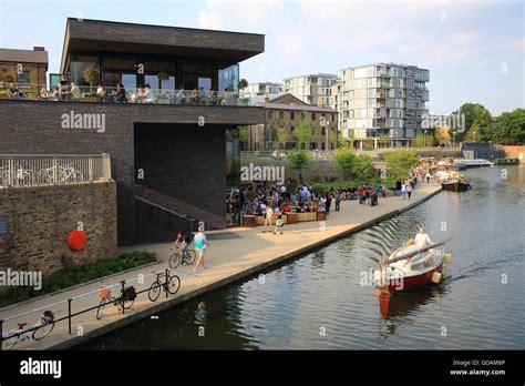 A boat sailing down the Regents Canal, past the Lighterman gastro-pub, at Kings Cross, London ...