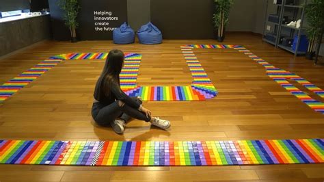 a woman sitting on the floor in front of an array of colored squares that look like rainbows