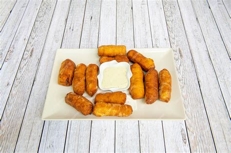 Premium Photo | White plate of toasted tequenos with sauce in the center