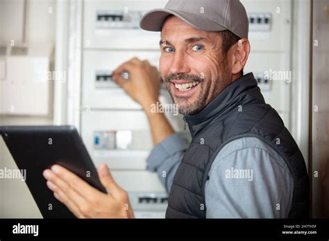 electrician smiling near switch box with tablet computor Stock Photo - Alamy
