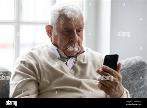 Old man holding smartphone look at device screen feels amazed Stock ...