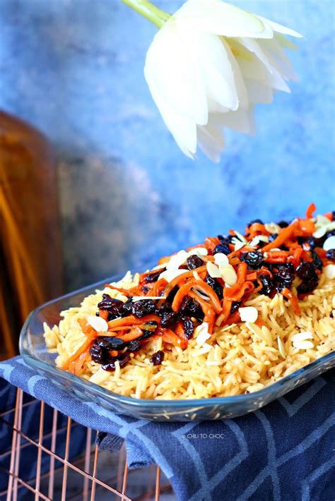 a bowl filled with rice and carrots next to a white flower