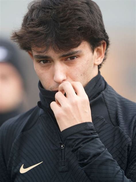 a close up of a person wearing a jacket and holding his hand to his face