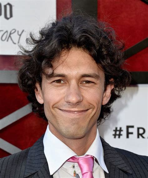 a man with curly hair wearing a suit and pink tie