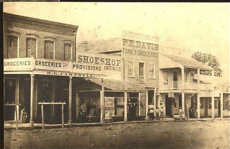 an old black and white photo of some shops in the middle of town with ...