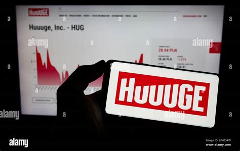 Person holding mobile phone with logo of Polish online games company HUUUGE Inc. on screen in ...