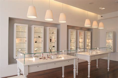 the inside of a jewelry store with glass shelves and lights above them ...