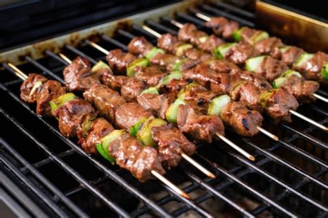 Premium Photo | Lamb skewers being brushed with marinade on a grill