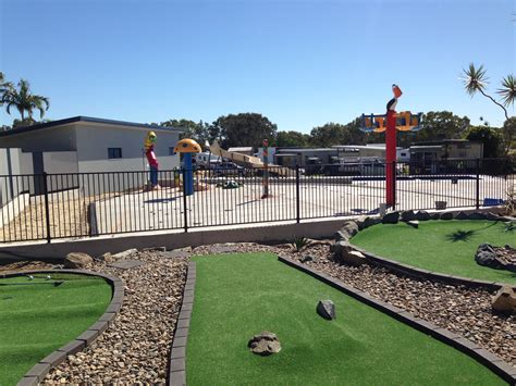 people playing miniature golf at the mini golf course in front of a motel or resort