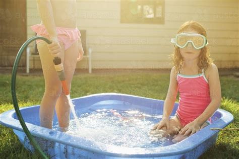 Image of Two girls playing in a wading pool - Austockphoto