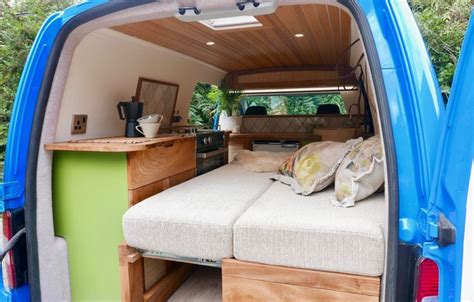 the interior of a blue van with two beds and storage compartments on it's side