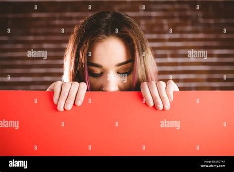 Woman looking at blank sheet against brick wall Stock Photo - Alamy