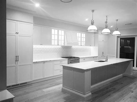 a large kitchen with white cabinets and an island in the middle is lit by three pendant lights