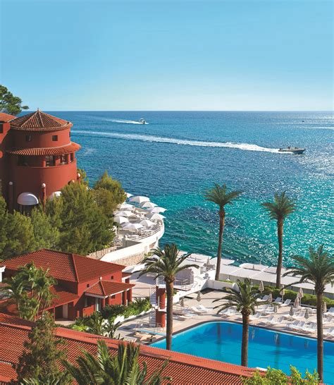 an aerial view of a resort with a pool in the foreground and boats on the water