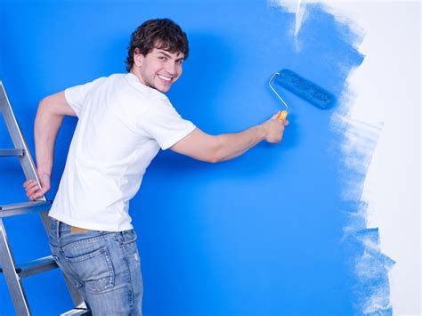 Free Photo | Handsome young man with happy smile painting the wall